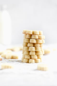 a stack of shortbread cookies sitting on top of a white table next to a glass of milk