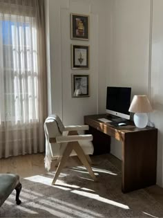 a desk with a computer on top of it in front of a curtained window