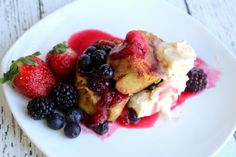 a white plate topped with fruit and ice cream covered in sauce on top of a wooden table