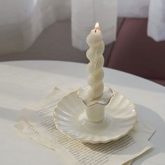 a lit candle sitting on top of a white plate