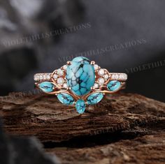 a turquoise and white stone ring sitting on top of a piece of wood with diamonds