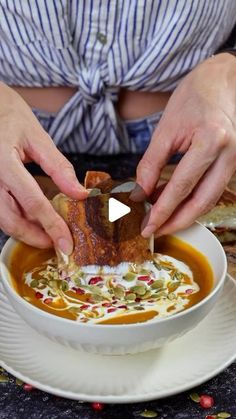 a person is dipping some kind of meat into a bowl of soup on a plate