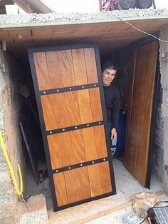 a man is standing in the doorway of a building that has been built with wooden doors