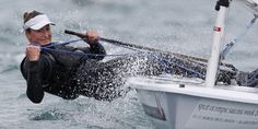 a woman is in the water on a sailboat