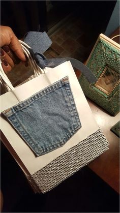 a person is holding a bag made out of old jeans and some other things on the table