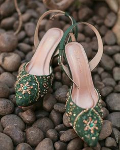 two pairs of green shoes sitting on top of rocks next to each other with beaded details