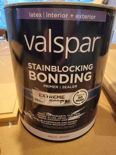 a black paint can sitting on top of a counter next to a window with the words valspar painted on it