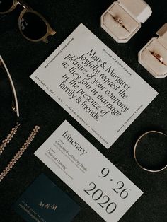 the wedding stationery is laid out on top of the table with rings and sunglasses