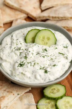 cucumber and dill dip in a bowl surrounded by pita chips