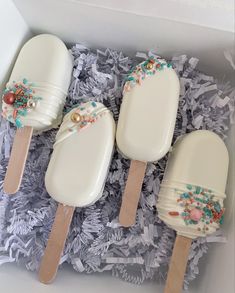 three ice cream pops in a box with sprinkles and pearls on them