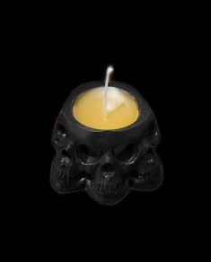 a candle with a skull on it in the middle of a black background, lit by a candle holder