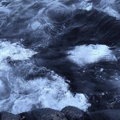 the water is very choppy and there are waves coming in from the rocks on the shore