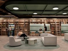 two people are sitting in the middle of a room with bookshelves and chairs