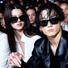 two women sitting next to each other in front of a group of people wearing sunglasses