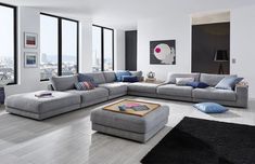 a living room filled with lots of furniture and large windows overlooking the cityscape