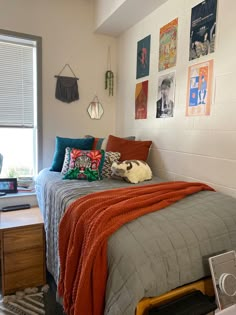 a bed sitting in a bedroom next to a window with pictures on the wall above it