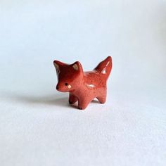 a small red ceramic animal on a white surface