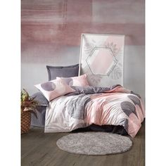 a bed with pink and grey comforters on top of it next to a round rug