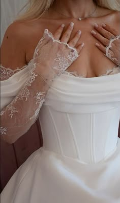 a woman in a white wedding dress with her hands on her chest