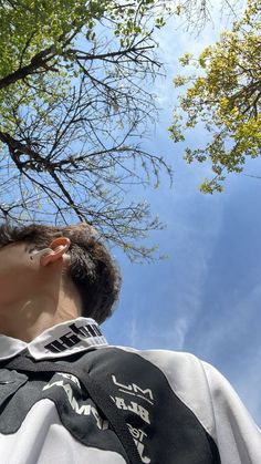 a man looking up into the sky with trees in the background