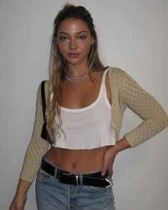 a woman with her hands on her hips wearing jeans and a white cropped top