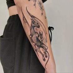 a woman with a dragon tattoo on her arm, holding onto a black and white photo