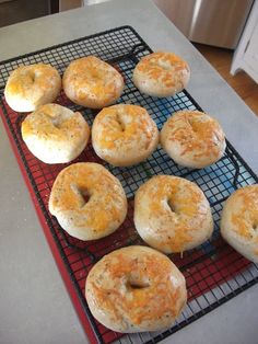 nine bagels on a cooling rack with cheese sprinkled on them, ready to be baked