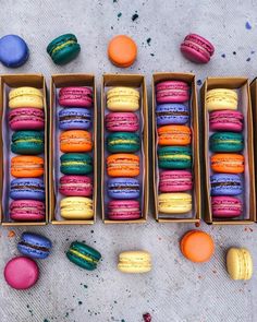 colorful macaroons are arranged in boxes on the ground