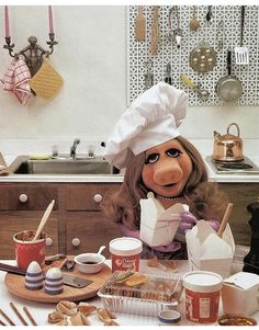 the muppet doll is sitting in front of some food and utensils on the table