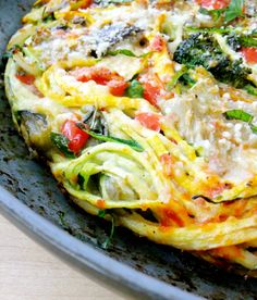 an omelet with vegetables and cheese in a pan