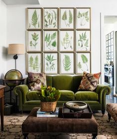 a living room with green couches and pictures on the wall above them, along with a coffee table