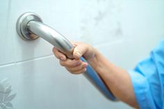 a person in scrubs holding onto a shower handle