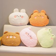 four different colored stuffed animals sitting on top of a white shelf next to each other