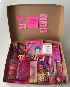 an open box with pink items and notes on the inside, including lipstick, toothbrushes, lip balm, mouthwash, gums, and more