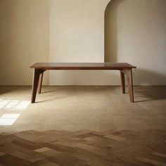 a wooden table sitting on top of a hard wood floor next to a white wall