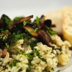 a white plate topped with rice covered in mushrooms and broccoli next to a slice of bread