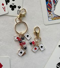 two pairs of playing cards are attached to gold - plated keychains with charms