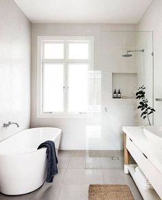 a white bath tub sitting next to a window in a bathroom