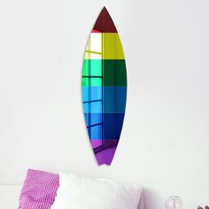 a rainbow surfboard hanging on the wall above a bed