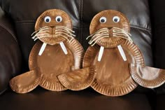 two paper plates shaped like animals sitting on top of a leather couch next to each other