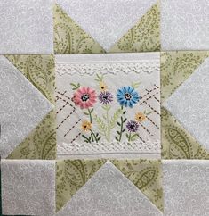 a close up of a patchwork quilt with flowers on the front and bottom corner