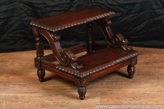 an antique wooden table with two tiered trays on each side and carved legs