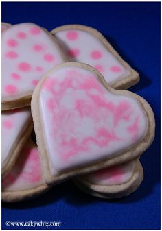 heart shaped cookies with pink and white icing on blue background for valentine's day