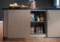 an open cabinet in the middle of a kitchen with food and condiments on it