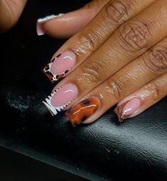 a woman's hand with pink and black nail polish on it, holding a leopard print manicure