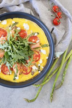 an omelet with tomatoes, spinach and feta cheese in a blue bowl