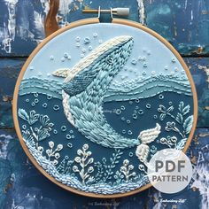 a hand embroidered whale in the ocean with bubbles