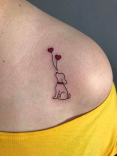 a woman's chest with a small tattoo of a dog holding a heart shaped balloon