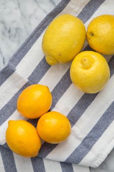 four lemons and three oranges sitting on a striped towel next to each other