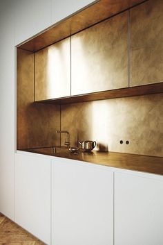 a kitchen with white cabinets and wooden flooring next to a wall mounted shelf filled with pots and pans